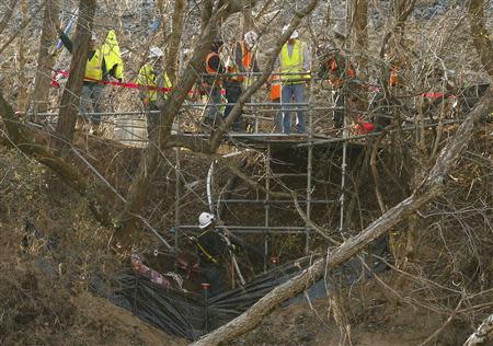 A worker looks up at his colleagues at the site of the retired Duke Energy coal-fired power plant where a second leak of coal ash was found in Eden, North Carolina February 19, 2014. North Carolina state officials defended their oversight of coal ash ponds on Wednesday, a day after a second leak was found to be threatening a river already tainted by toxic sludge from a spill earlier this month. REUTERS/Chris Keane