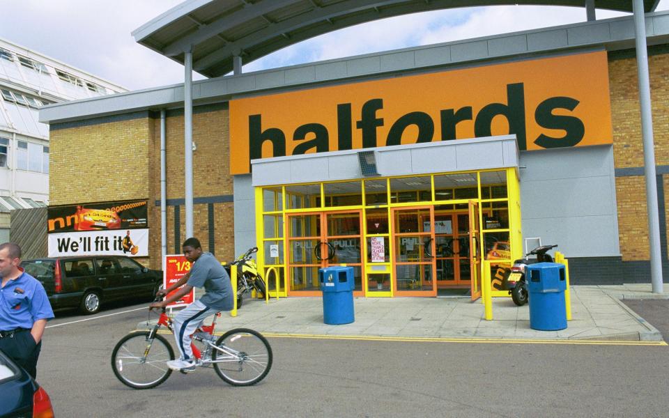 A man rides a bike outside a Halfords store - Credit: Marina Imperi/Marina Imperi