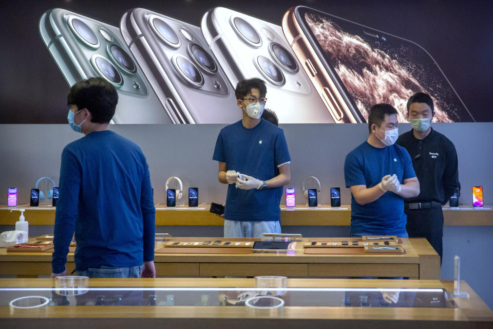 Employees wear face masks as they stand in a reopened Apple Store in Beijing, Friday, Feb. 14, 2020. China on Friday reported another sharp rise in the number of people infected with a new virus, as the death toll neared 1,400. Apple had closed all of its stores in China in early February amid concerns over a virus outbreak. (AP Photo/Mark Schiefelbein)