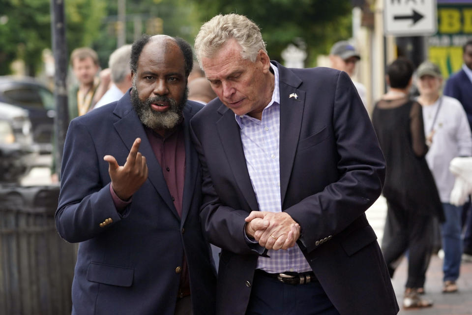 FILE - In this May 29, 2021, file photo, Democratic gubernatorial candidate, former Gov. Terry McAuliffe, right, talks with former Delegate Fenton Bland, during a tour of downtown Petersburg, Va. McAuliffe won Virginia's 2013 governor's race by embracing his own brand of personal politics that rely on decades-old friendships, back-slapping charisma and tell-it-like-it-is authenticity. (AP Photo/Steve Helber, File)