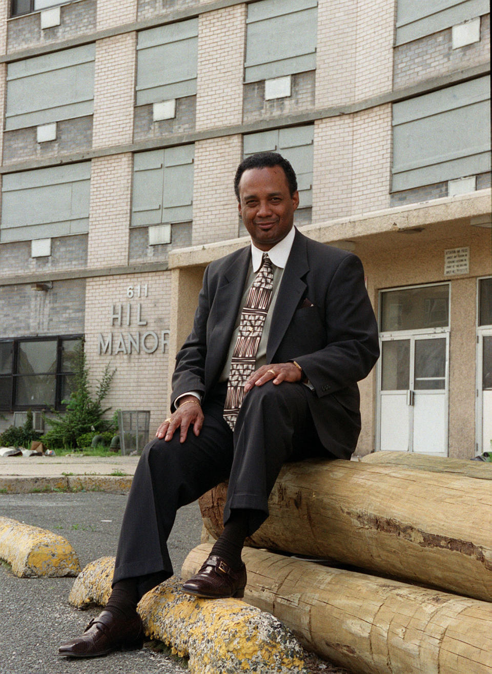 In this May 15, 1999 photo, Donald Bernard Sr., chairman of the African American Heritage Parade, poses outside of the defunct Hill Manor where he once lived in Newark, N.J. As a Democratic presidential candidate, Booker has leaned heavily on his record as Newark mayor. But the watershed scandal still burns some of his critics in New Jersey. Bernard Sr., pleaded guilty to accepting $957,000 from contractors for help getting them work. (Samir Id-Deen/NJ Advance Media via AP)