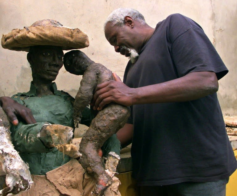 Senegalese sculptor Ousmane Sow arranges the baby of a couple as he works on a project in Dakar in 2001