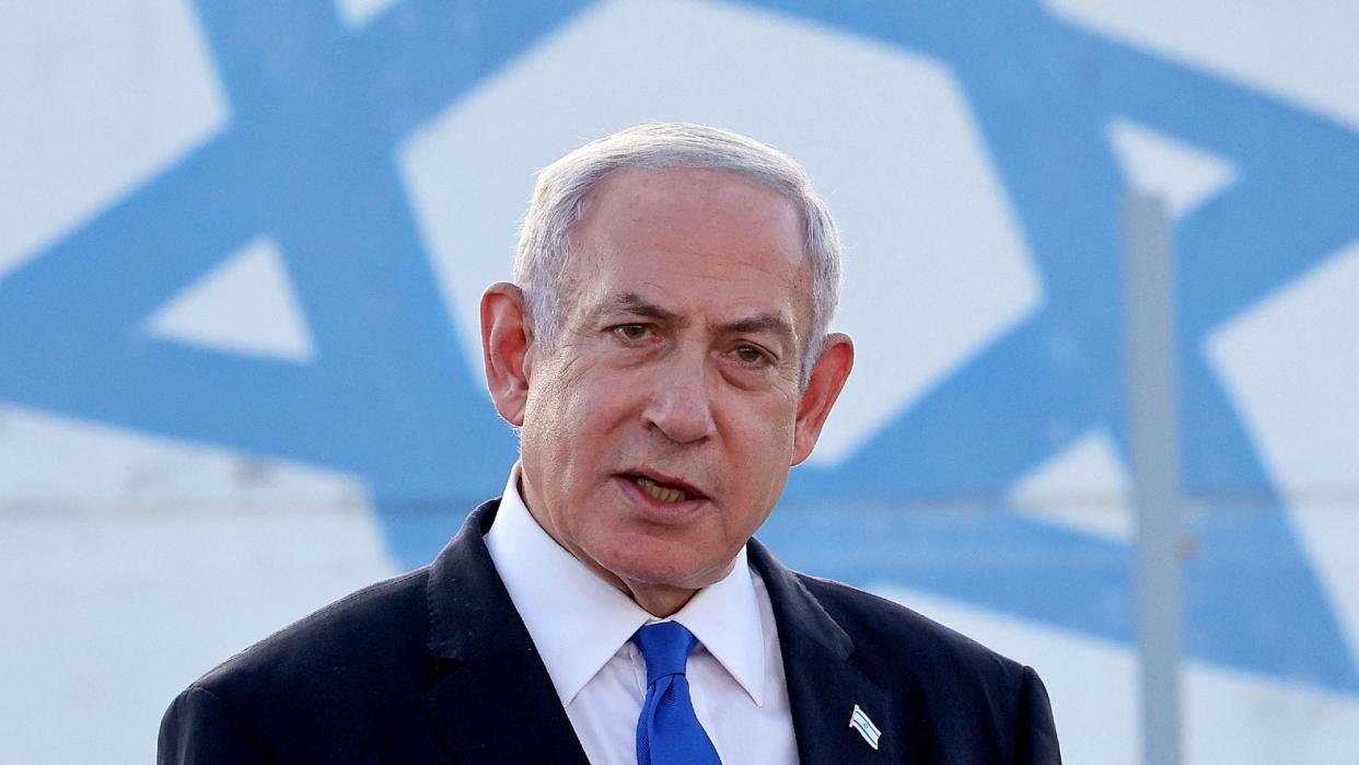  Israel's Prime Minister Benjamin Netanyahu standing in front of the Israeli flag. 