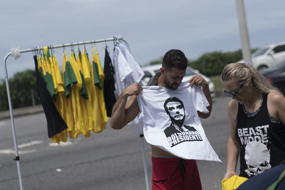 A man buys a T-shirt with an image depicting Brazil's presidential frontrunner Jair Bolsonaro, at the Barra beach, in Rio de Janeiro, Brazil, Sunday, Oct. 7, 2018. Brazilians choose among 13 candidates for president Sunday in one of the most unpredictable and divisive elections in decades. If no one gets a majority in the first round, the top two candidates will compete in a runoff. (AP Photo/Leo Correa)