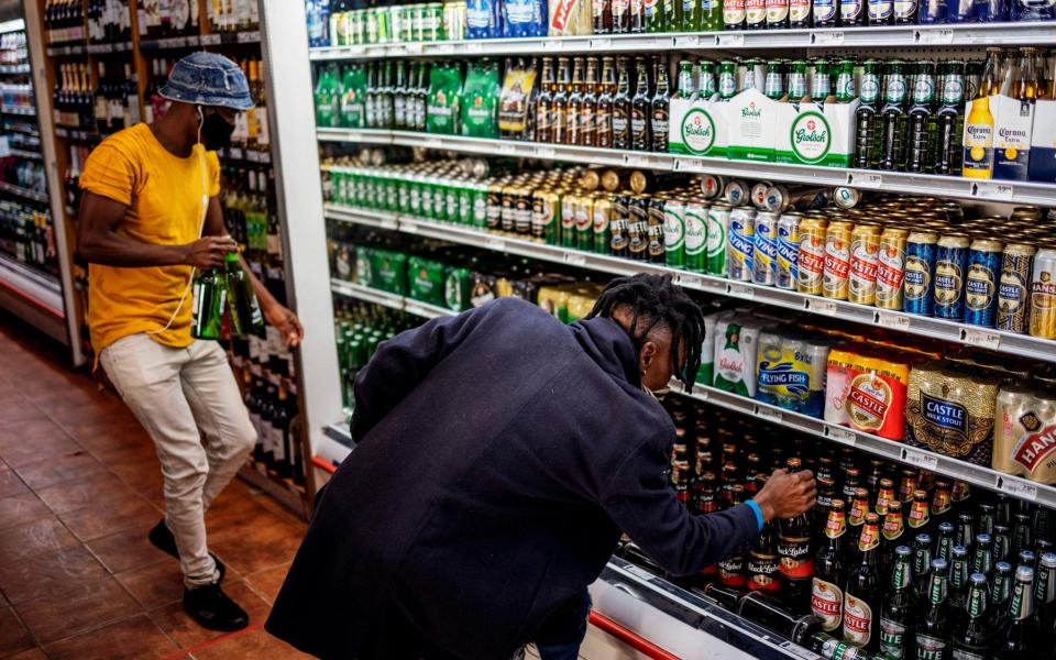 Customers buy alcohol at a liquor shop at the Bara taxi rank in Soweto, Johannesburg - AFP