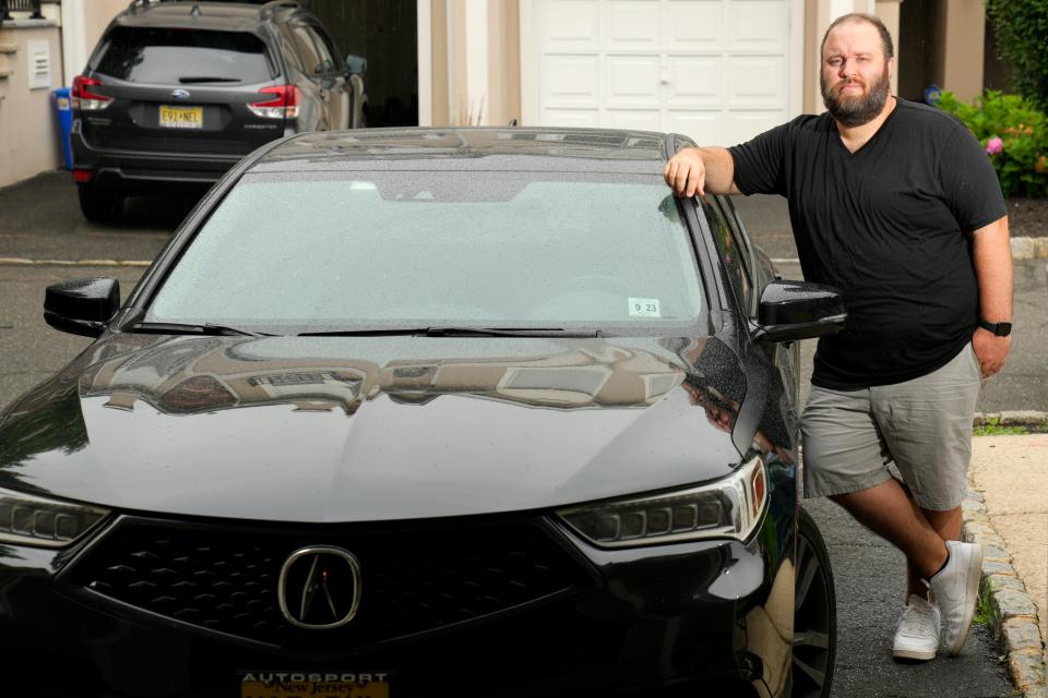 Tim DeMuth poses for a photograph beside his car, in front of his Clifton home. Wednesday, July, 19, 2023 