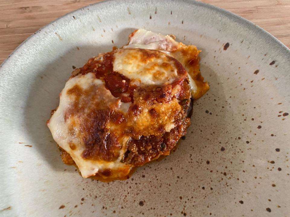 Eggplant Parmesan on a gray plate with spots.