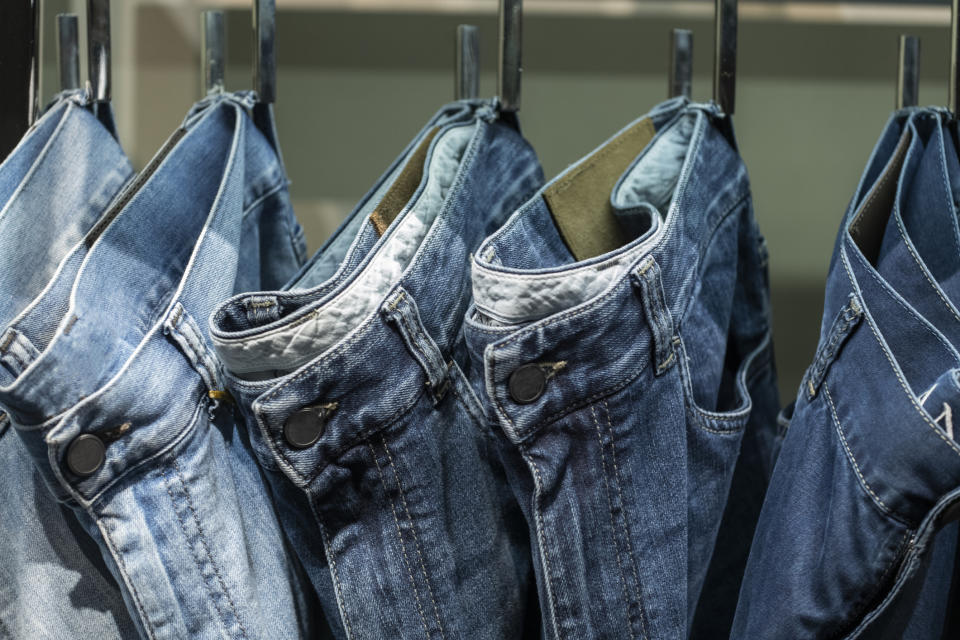 A rack displaying several pairs of blue jeans hung closely together by their belt loops