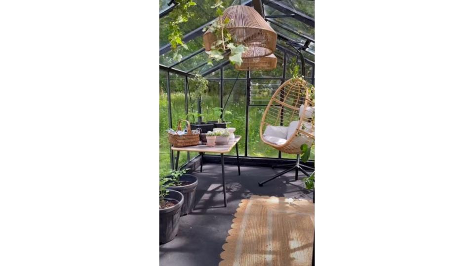 Stacey Solomon inside of greenhouse with hanging lamps and egg chair