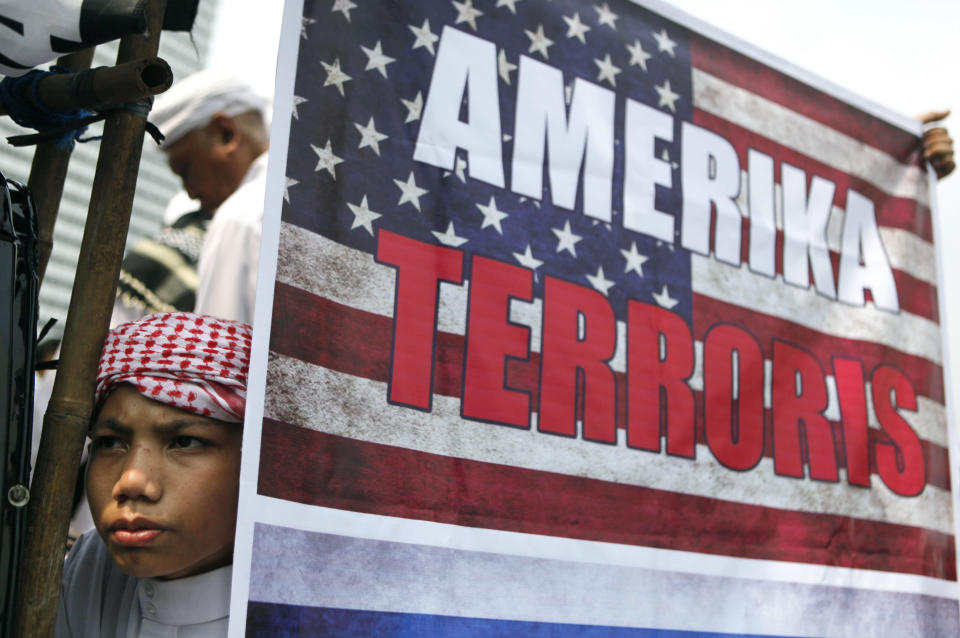 A Muslim youth pauses near a poster during a protest against an anti-Islam film in Jakarta, Indonesia, Monday, Sept. 17, 2012. Indonesians enraged over an anti-Islam film hurled rocks and Molotov cocktails at the U.S. Embassy in Jakarta on Monday, marking the first violence in the world's most populous Muslim country since outrage exploded last week in the Middle East and beyond. (AP Photo/Dita Alangkara)