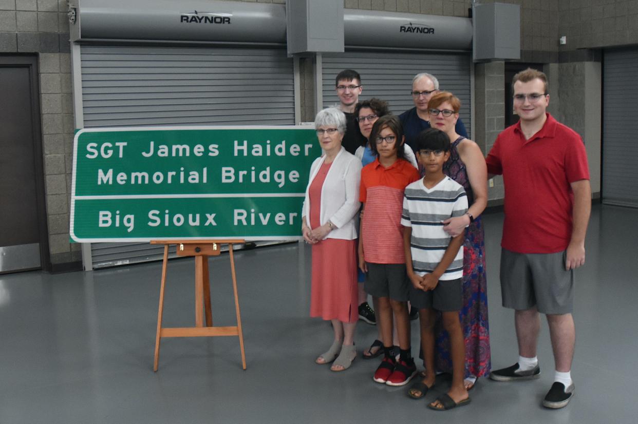 Family members revealed the sign dedicating the new U.S. Highway 212 bridge after their fallen loved one, U.S. Army Sgt. James Haider. Back row from left are Carson, Stewart and Braeden Schramm; middle row from left, Lynnell Schramm and Michelle Ally; front row from left, Katie Mack and Mac and Myles Ally.