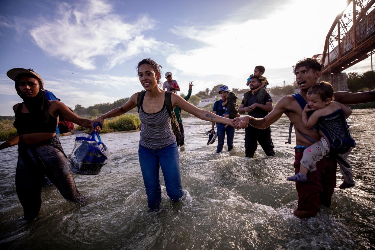 Migrants hold hands for safety as they cross the Rio Grande River into the U.S. in Eagle Pass, Texas on Thursday from Piedras Negras, Coahuila, Mexico. The migrants were part of a group of nearly 30 hoping to seek asylum in the U.S.