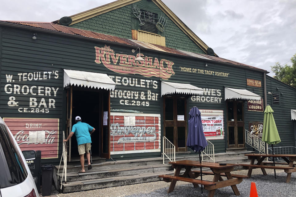 A customer enters the Rivershack Tavern, the first day restaurants are allowed to provide indoor sit-down service, in Jefferson, La., Friday, May 15, 2020. Once a hot spot for coronavirus infections, Louisiana is officially easing up Friday on economically devastating business closures and public gathering restrictions that Gov. John Bel Edwards credits with slowing the spread of the virus. (AP Photo/Kevin McGill)