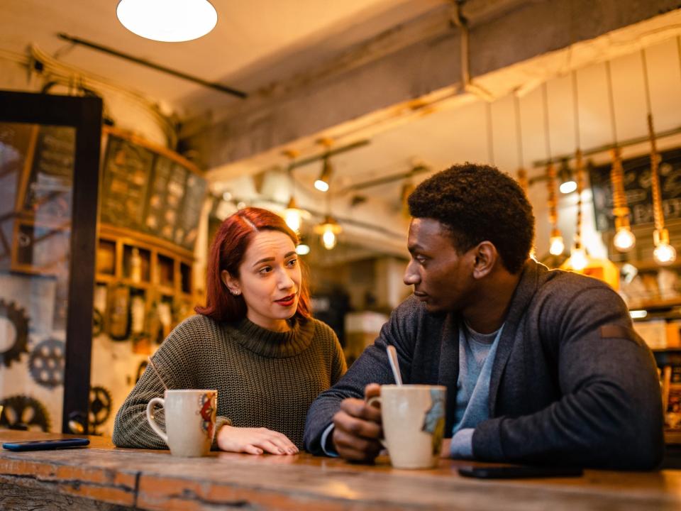 Two people talking in a coffee shop setting.