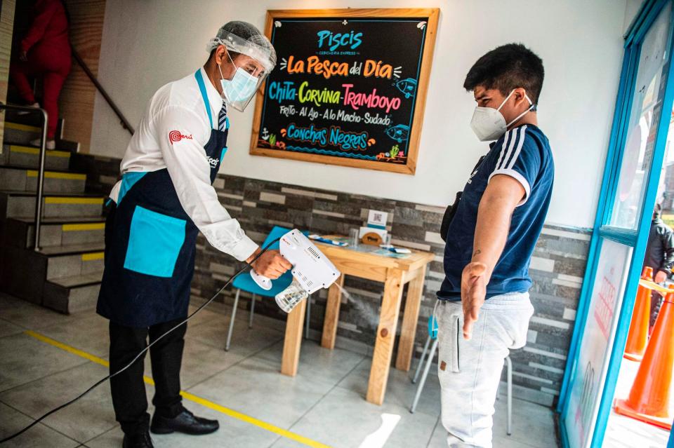 A waiter disinfects a customer as he enters a restaurant in Lima on July 20, 2020, amid the new coronavirus pandemic. - The restaurants of Peru, a country with world famous gastronomy, reopened their doors Monday after four months of confinement due to the new coronavirus pandemic, but hundreds did not manage to survive the quarantine. (Photo by ERNESTO BENAVIDES / AFP) (Photo by ERNESTO BENAVIDES/AFP via Getty Images)