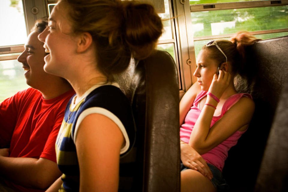 Young girl sitting on a school bus listening to music