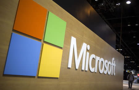 An attendee at the Microsoft Ignite technology conference is seen next to the Microsoft logo in Chicago, Illinois, May 4, 2015. REUTERS/Jim Young