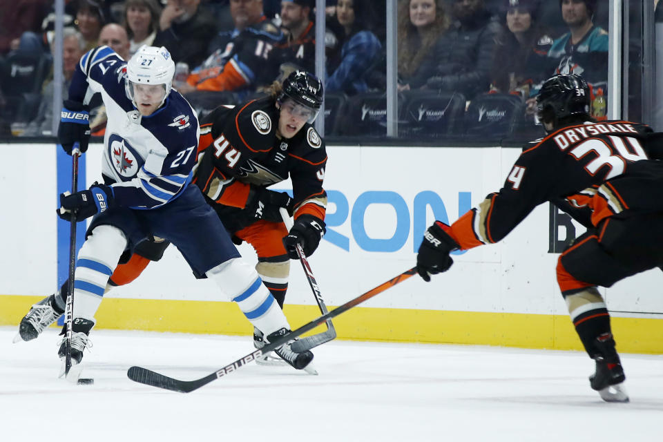 Winnipeg Jets left wing Nikolaj Ehlers (27) controls the puck away from Anaheim Ducks left wing Max Comtois (44) and defenseman Jamie Drysdale (34) during the first period of an NHL hockey game in Anaheim, Calif., Tuesday, Oct. 26, 2021. (AP Photo/Alex Gallardo)