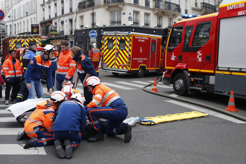 Firefighters tends to a wounded person near the site of a gas leak explosion in Paris, France, Saturday, Jan. 12, 2019. A powerful explosion and fire apparently caused by a gas leak at a Paris bakery Saturday injured several people, blasted out windows and overturned cars, police said. (AP Photo/Thibault Camus)