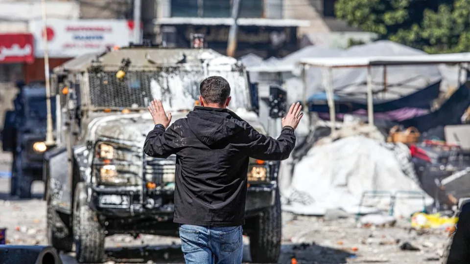 Un joven palestino frente a un vehículo del ejército israelí en Nablus.
