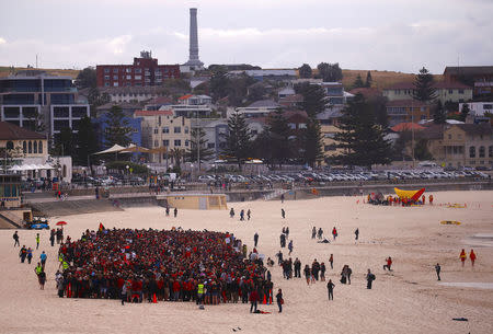 FILE PHOTO: Surf lifesavers can be seen behind protesters participating in a national Day of Action against the Indian mining company Adani's planned coal mine project in north-east Australia, at Sydney's Bondi Beach in Australia, October 7, 2017. REUTERS/David Gray/File Photo