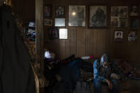 With framed family photos hanging on the wall, 80-year-old Clifford Weyiouanna, a respected village elder and former reindeer herder, rests on a sofa in his home in Shishmaref, Alaska, Saturday, Oct. 1, 2022. (AP Photo/Jae C. Hong)
