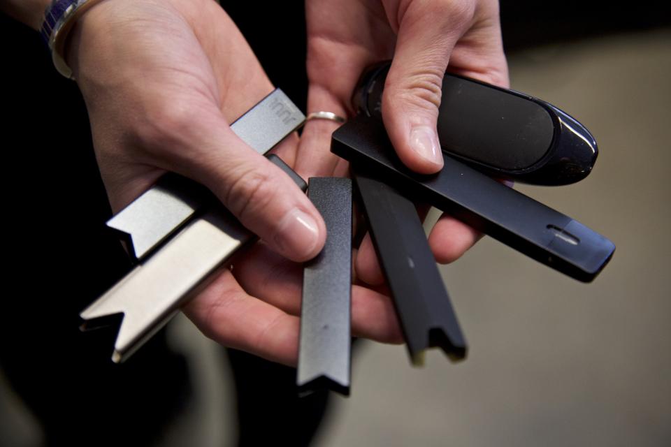 File - In this April 16, 2019, file photo, a researcher holds vape pens in a lab at Portland State University in Portland, Ore. Today Juul and hundreds of smaller companies are at the center of a political backlash that threatens to sweep e-cigarettes from stores shelves nationwide as politicians scramble to address two separate public health crises tied to vaping: underage use among teenagers and a mysterious and sometimes fatal lung ailment that affected more than a thousand people. (AP Photo/Craig Mitchelldyer, File)