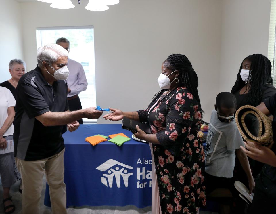 Jasmie Cooper, right, accepts the keys to her new Habitat for Humanity home from Saeed Khan, left, a board member of Habitat for Humanity, during a ceremony at the new home in Gainesville on May 18.