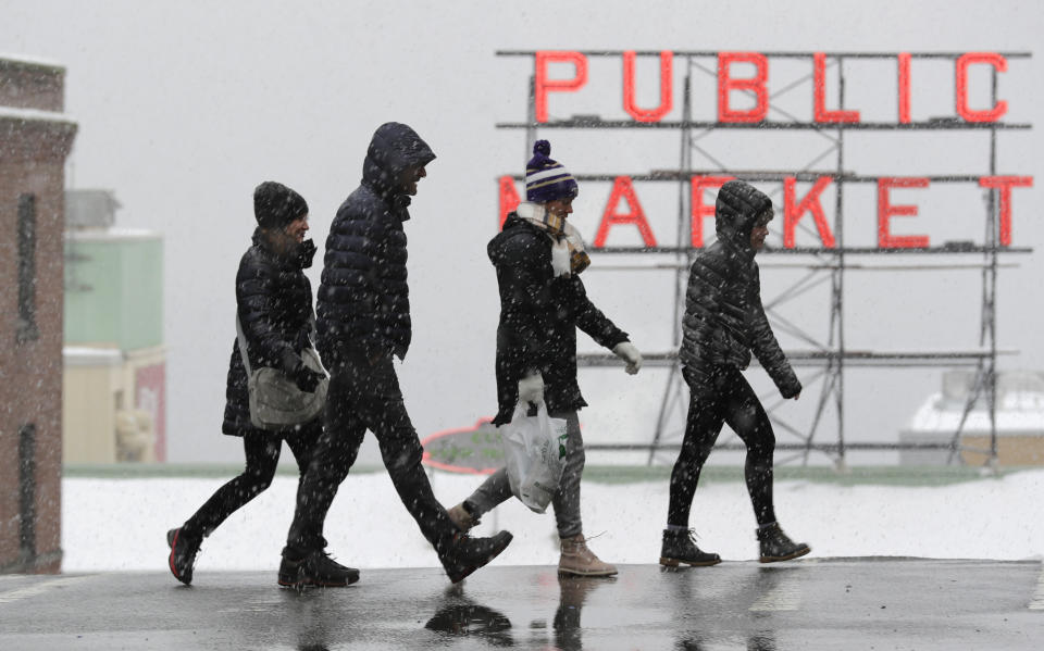 Pedestrians walk near Pike Place Market as snow falls Monday, Feb. 11, 2019, in downtown Seattle. Schools were closed across Washington state as winter snowstorms continued pummeling the Northwest. Seattle's metro area has already been hit by three snowstorms in February, making it the snowiest month in Seattle in more than 30 years. (AP Photo/Ted S. Warren)