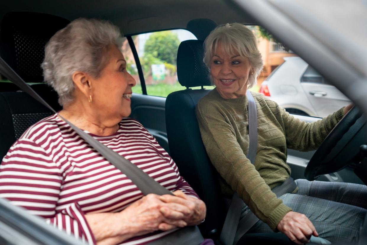 Happy Latin American senior women going out for a drive in their car and smiling - lifestyle concepts