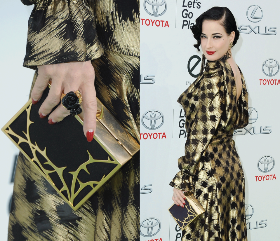 Dita Von Teese s’y connaît. Avec sons sens aigu de la mode, elle a craqué pour un clutch épais noir et doré au motif végétal. Un accessoire qui habille parfaitement sa robe.