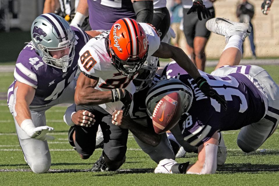Oklahoma State receiver Brennan Presley (80) fumbles the ball as he is tackled by Kansas State linebacker Austin Moore (41) and defensive end Brendan Mott (38) during the first half of a 48-0 loss Saturday in Manhattan, Kan. Kansas State recovered the fumble.