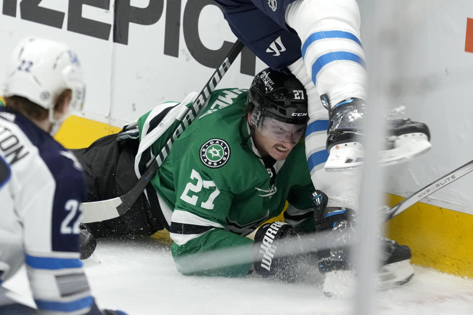 Dallas Stars left wing Mason Marchment (27) is slammed against the boards by Winnipeg Jets' Logan Stanley, top, as Jets' Mason Appleton (22) looks on in the second period of an NHL hockey game in Dallas, Thursday, April 11, 2024. (AP Photo/Tony Gutierrez)