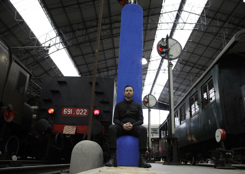 In this picture taken on Thursday, April 11, 2019, Spanish designer Fernando Mastrangelo poses sitting on his creation 'Tombstone Chair', at the National Museum of Science and Technology, for the "RO Plastic - Master's Pieces" exhibition, on the sidelines of Milan's Furniture Fair, in Milan, Italy. Scientists and environmental activists have been long raised the alarm on plastic pollution. Now, the high-end design world is getting in on the growing global effort to tackle plastic pollution -- by upcycling discarded objects into desirable one-off design pieces. (AP Photo/Luca Bruno)