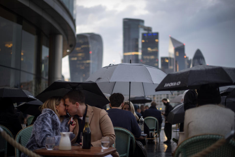 People endure the wet and windy Bank Holiday weekend weather to sit outside a restaurant near Tower Bridge in central London on Monday, May 3, 2021. (Victoria Jones/PA via AP)