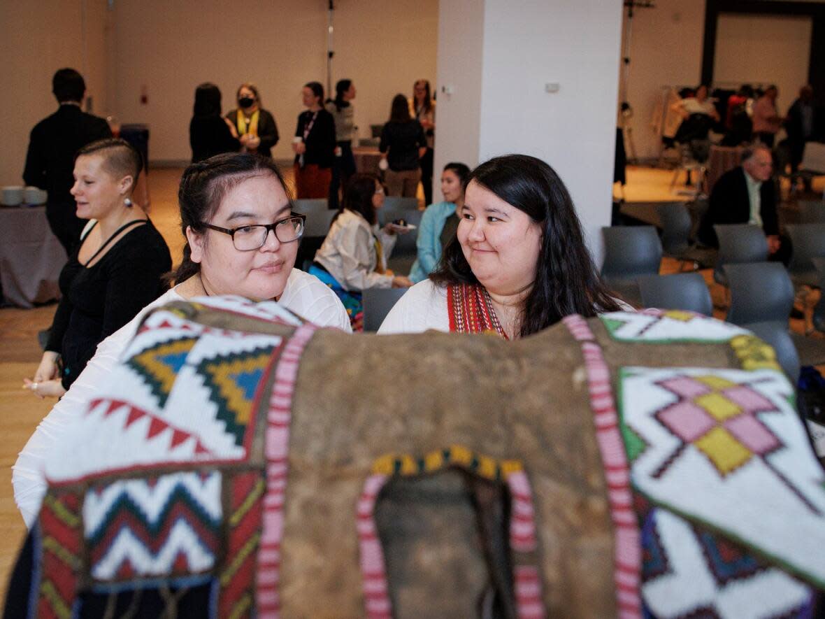 Nikita Ashley Poundmaker, left, and lawyer and family friend Lawren Trotchie look at a saddle during a repatriation ceremony at the Royal Ontario Museum, in Toronto, on Feb. 22, 2023. A pipe and saddle belonging to Chief Poundmaker were returned to the family from the ROM collections.  (Evan Mitsui/CBC - image credit)