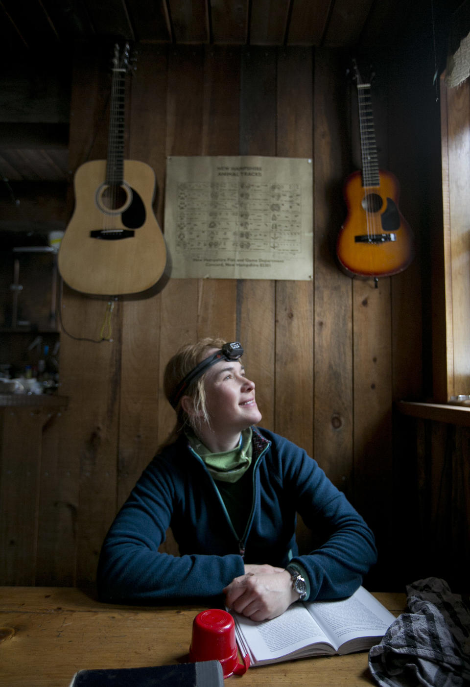 In this Friday, April 4, 2014 photo, Ania Kowalczyk, of Quebec City, looks out of a window to check on the weather during a stay at the Gray Knob cabin in New Hampshire. The remote cabin, located just below the tree line, is a welcomed haven for hikers waiting out foul weather. (AP Photo/Robert F. Bukaty)