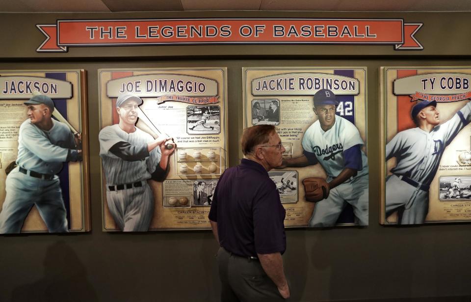 FILE - This Oct. 22, 2013 file photo shows visitors to the St. Petersburg History Museum view some of Dennis Schrader's autographed baseballs in St. Petersburg, Fla. There are many destinations of interest to baseball fans around the country outside ballparks from museums and statues to historic homes. (AP Photo/Chris O'Meara, File)