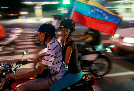 Opposition supporters ride on a motorcycle after an unofficial plebiscite against President Nicolas Maduro's government and his plan to rewrite the constitution, in Caracas, Venezuela July 16, 2017. REUTERS/Marco Bello