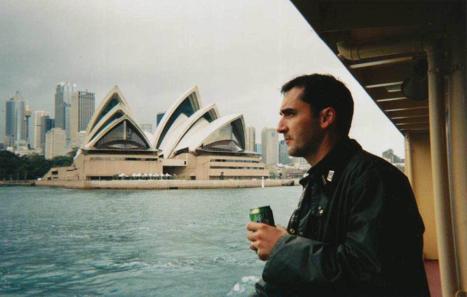 Chip Sutherland is shown in a 1999 photo from Sydney, Australia, with the iconic Sydney Opera House behind him.