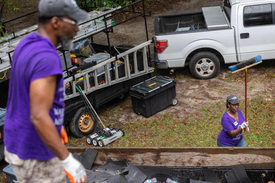 Shawna Hayes tosses a push broom up to her husband Tony Hayes while volunteering with Home Works of America on Saturday, May 20, 2023. While Tony was on the roof removing shingles, Shawna gathered the detritus.