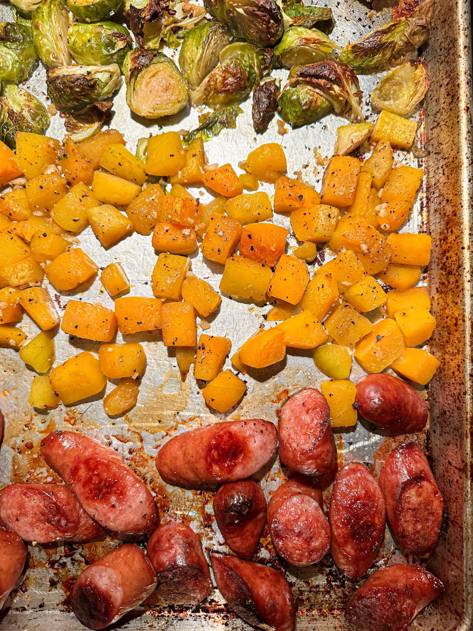 sausage, squash, and brussels sprouts on the sheet pan, after they're done cooking and golden brown