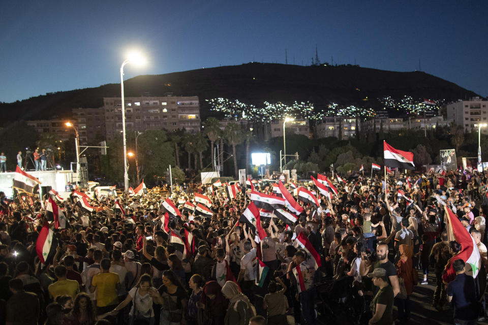 Syrian President Bashar Assad supporters hold up national flags and pictures of Assad they celebrate at Omayyad Square, in Damascus, Syria, Thursday, May 27, 2021. (AP Photo/Hassan Ammar)