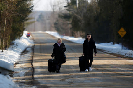 People walk with their luggage on Roxham Road before crossing the US-Canada border into Canada in Champlain, New York, U.S., February 14, 2018. REUTERS/Chris Wattie