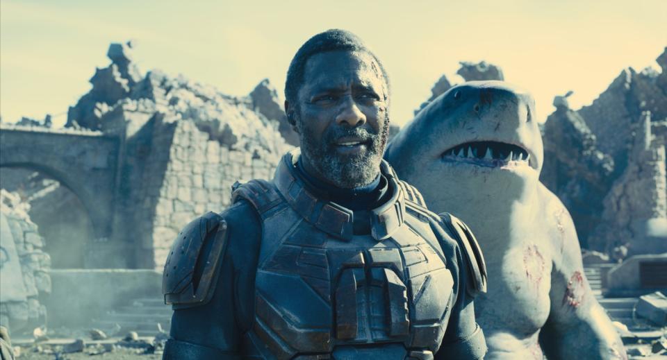 Idris Elba stands next to a shark man