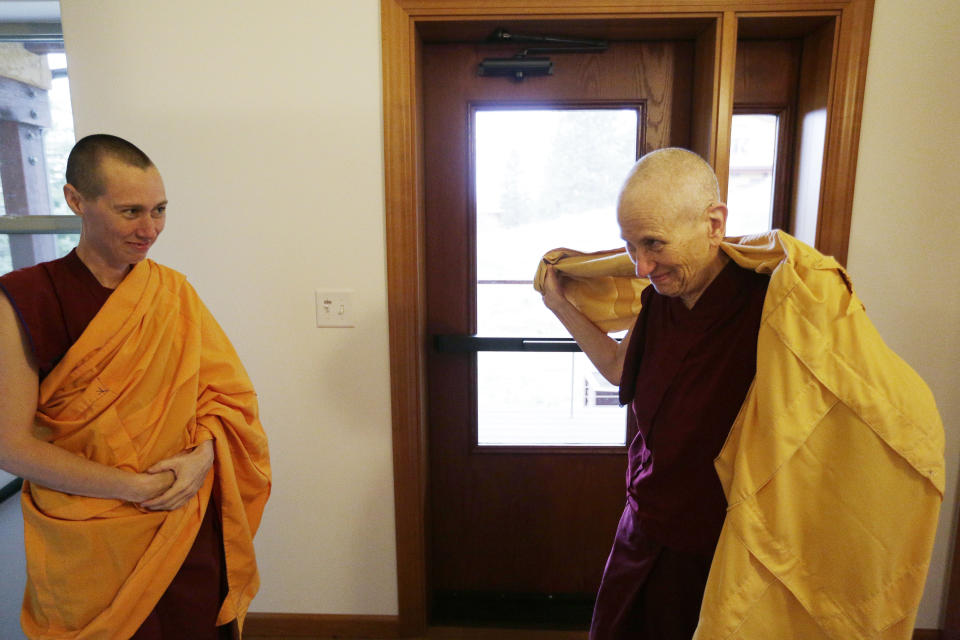 Venerable Thubten Chodron, right, a fully ordained Buddhist nun, founder and abbess of Sravasti Abbey, puts on her chogu before teaching the dharma, as Thubten Dekyi looks on, Thursday, Nov. 18, 2021, in Newport, Wash. (AP Photo/Young Kwak)