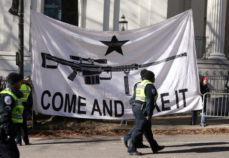 Law enforcement officers walk past a banner that reads "Come and Take It" after gun rights advocates and militia members attended a rally in Richmond, Virginia