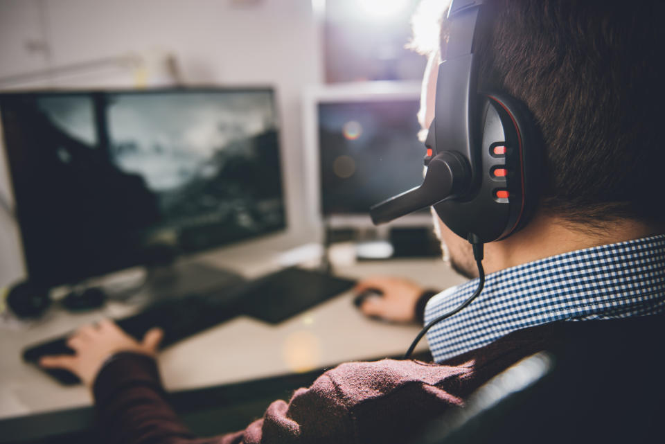 A man wearing a headset and playing a video game on a computer.