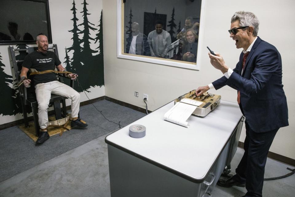 A man strapped into a chair, left, and a man in a suit next to a desk with a machine on it