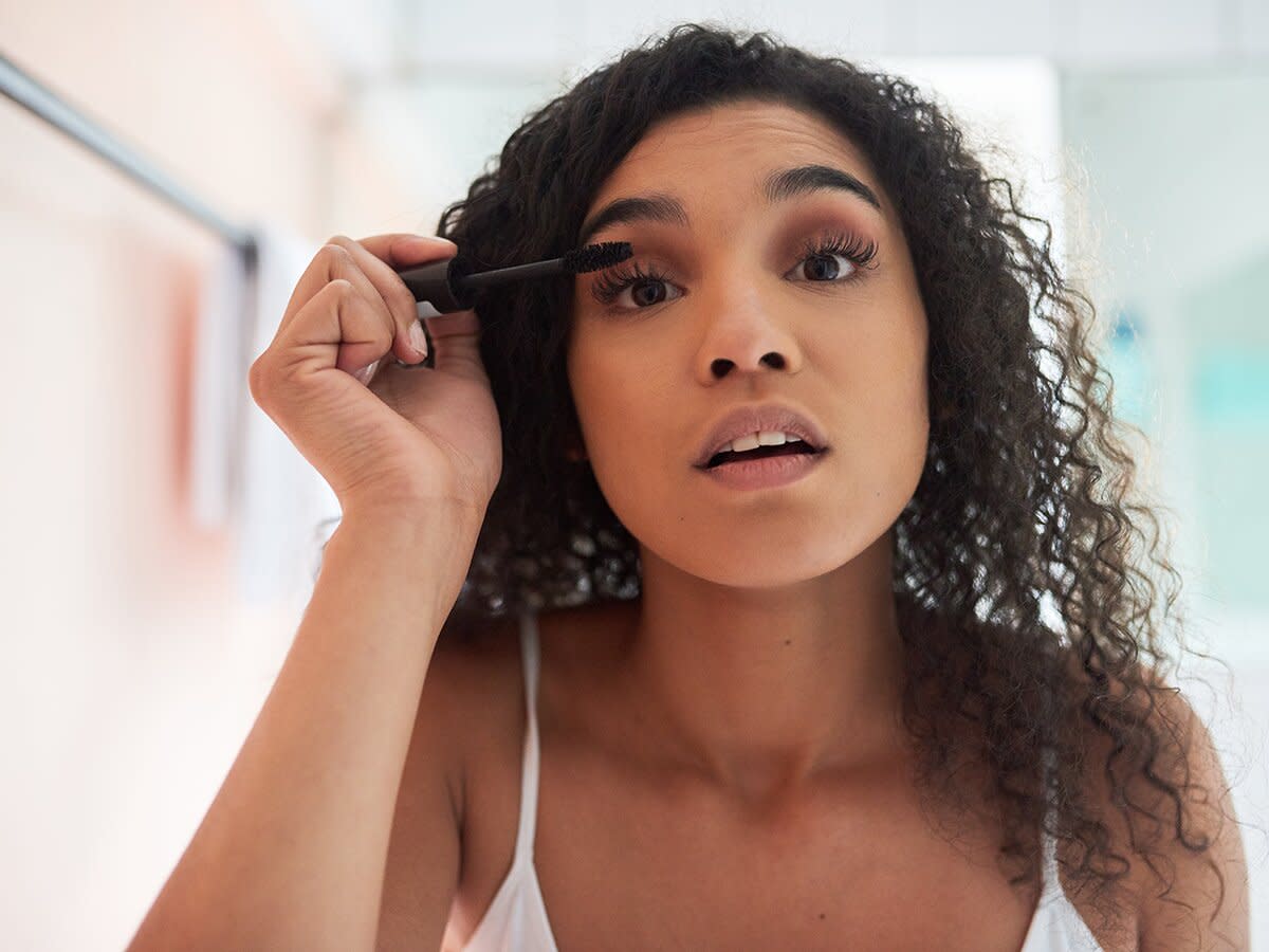 attractive young woman applying mascara